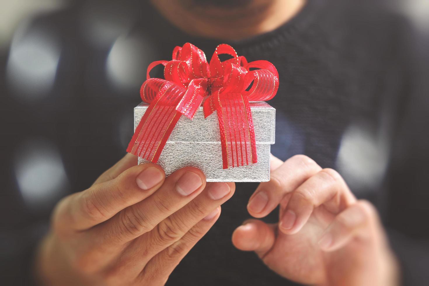 gift giving,man hand holding a gift box in a gesture of giving.blurred background,bokeh effect photo