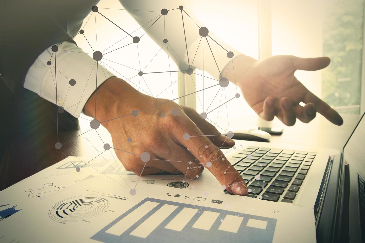 businessman hand working with business documents on office table with laptop computer with social media diagram photo