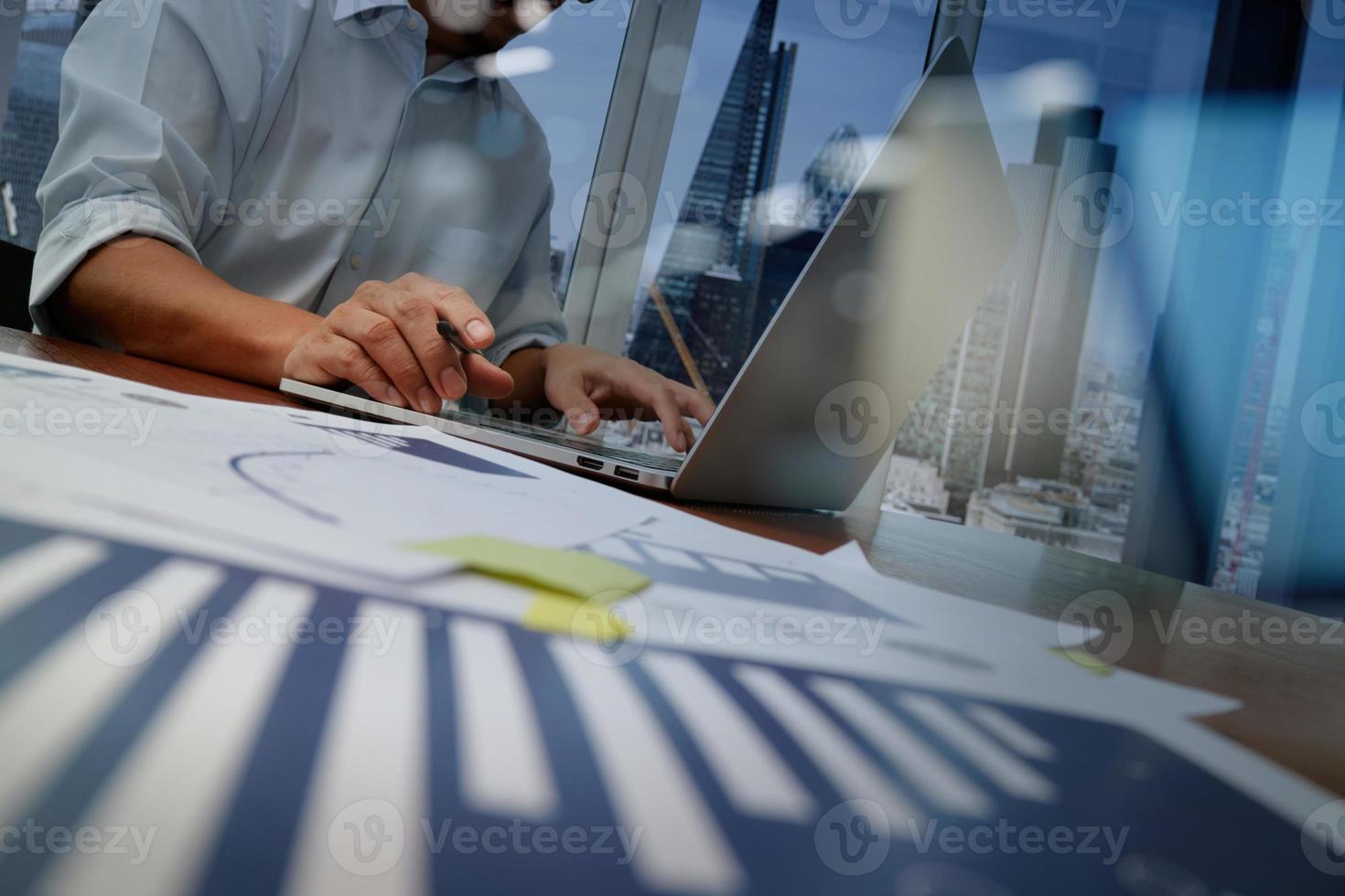 business documents on office table with smart phone and laptop computer and graph business with social network diagram and man working in the background photo