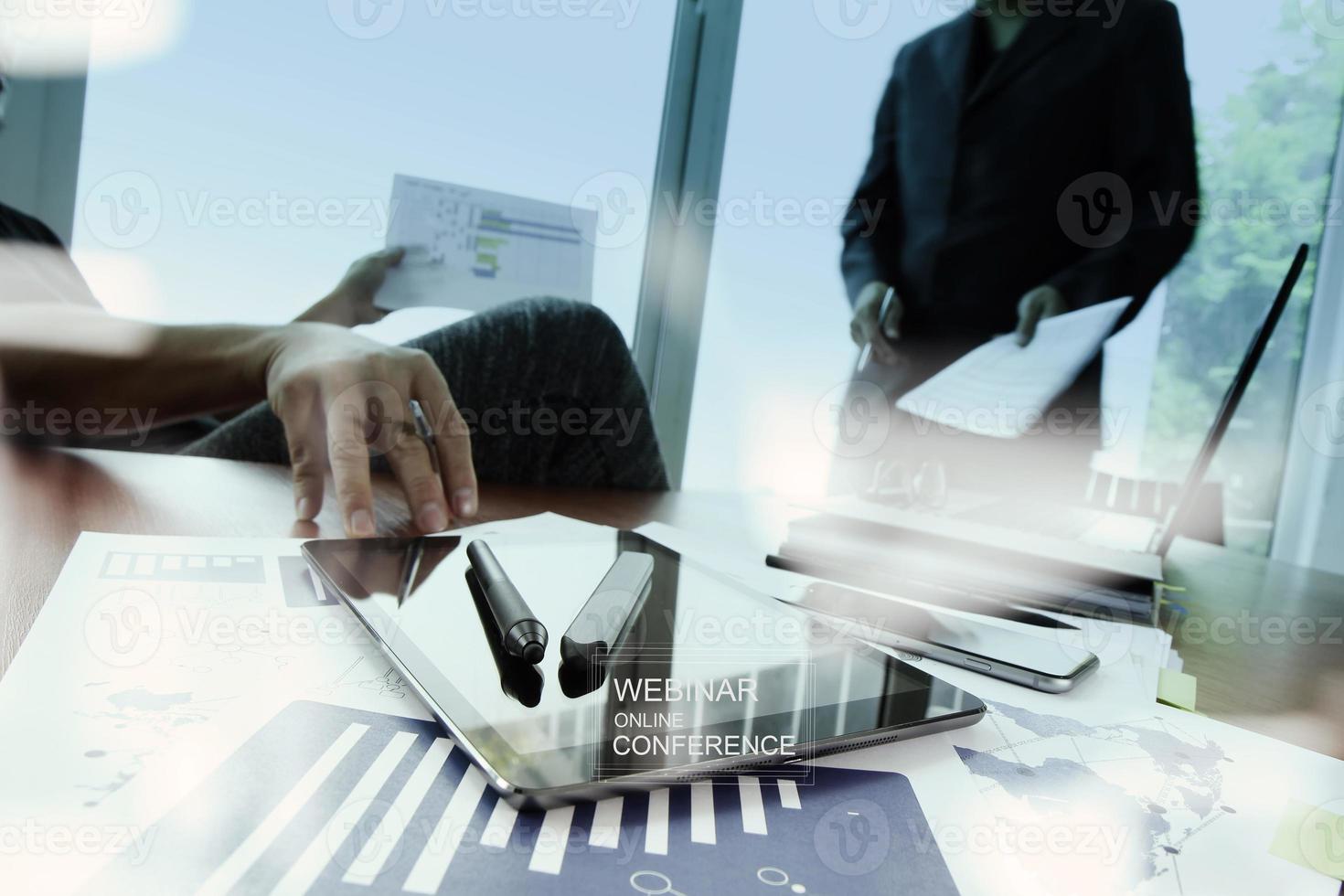 documentos comerciales en la mesa de la oficina con teléfono inteligente y computadora portátil y dos colegas discutiendo datos en segundo plano foto