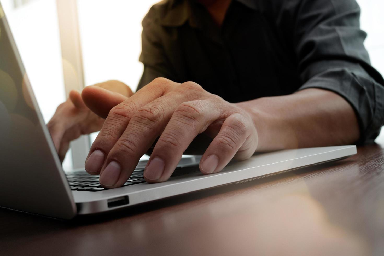 designer hand working and smart phone and laptop on wooden desk in office photo