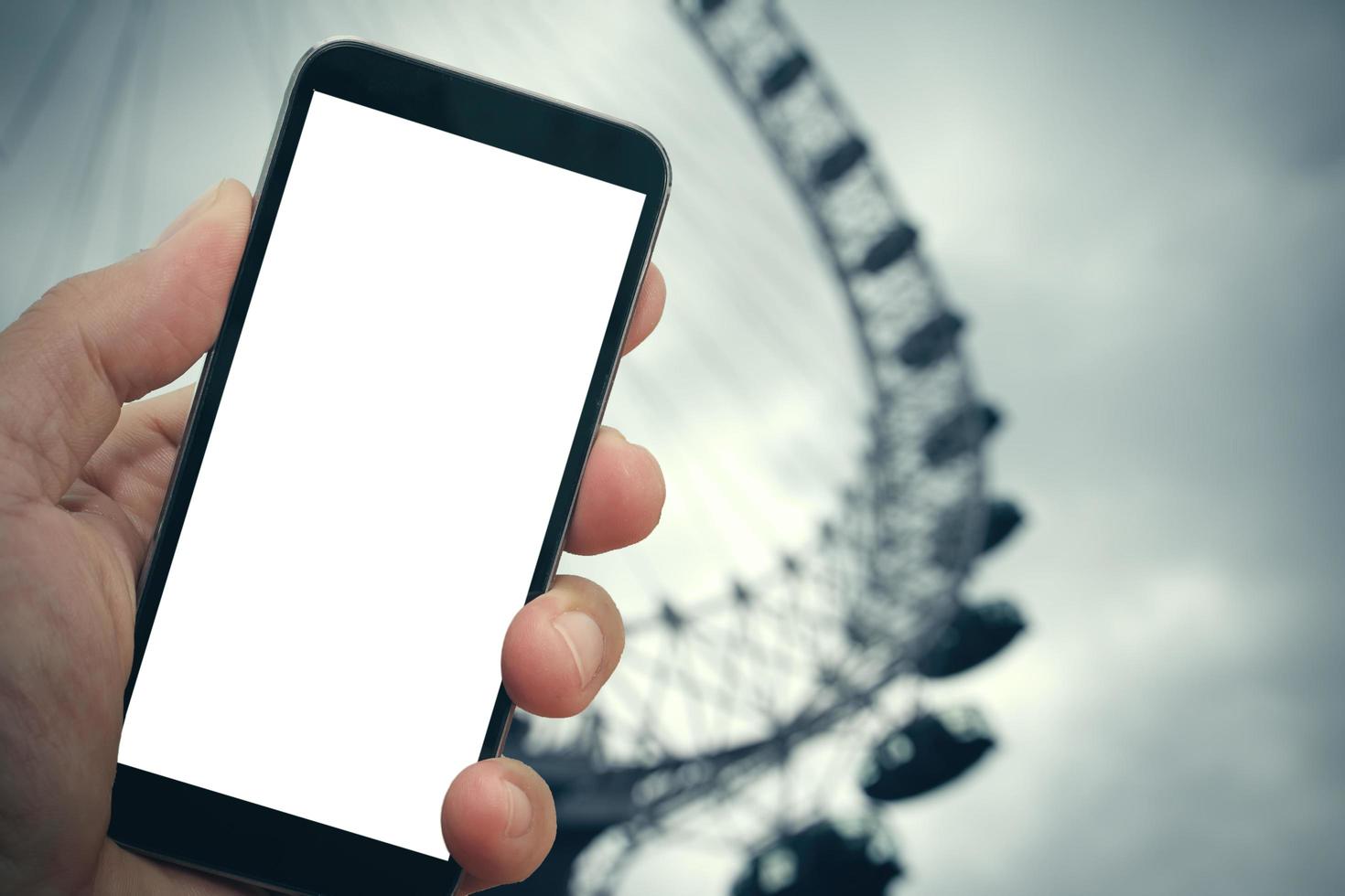 man hand holding blank screen smartphone against london city blurred background photo