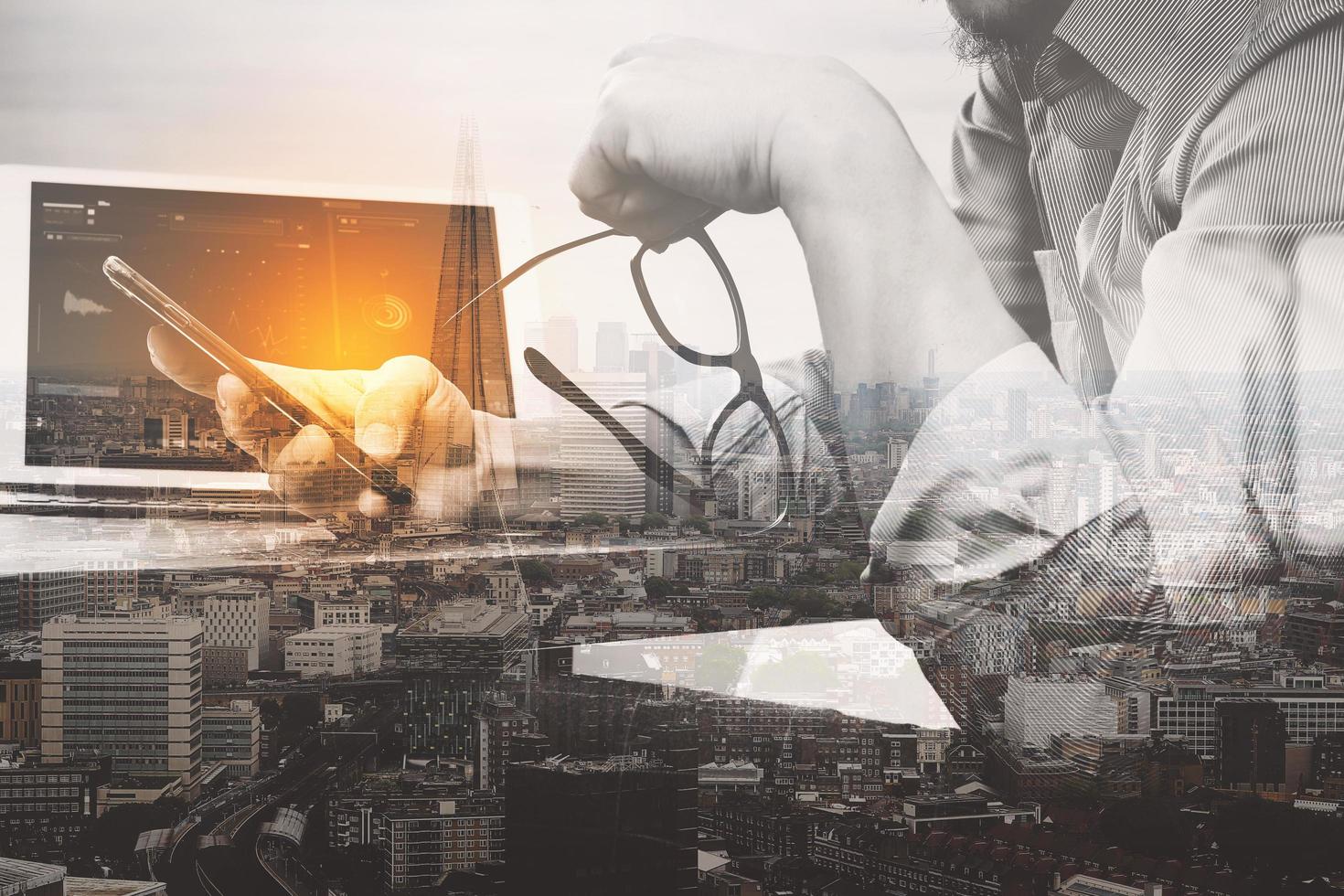 Double exposure of success businessman using eyeglass,digital tablet docking smart keyboard,smart phone with London building,city,filter effect photo