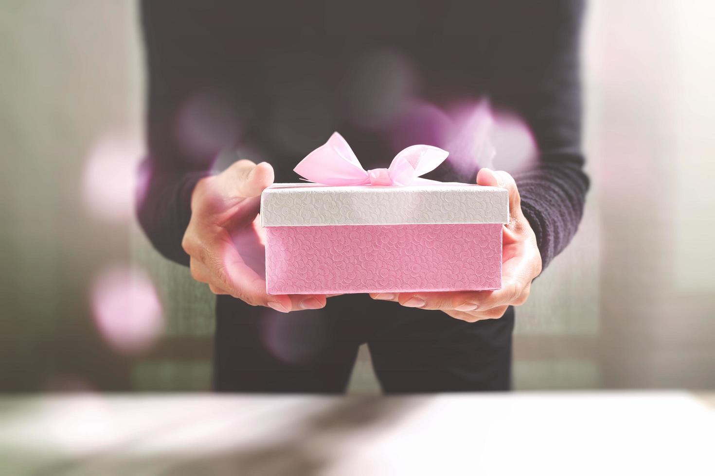 gift giving,man hand holding a gift box in a gesture of giving.blurred background,vintage effect photo