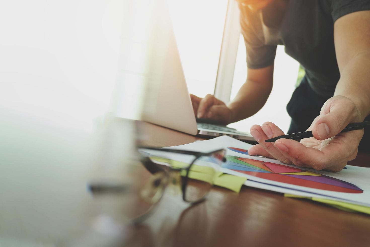 businessman hand working with new modern computer and business strategy documents digital layer with eyeglass and glass of water foreground on wooden desk in office photo