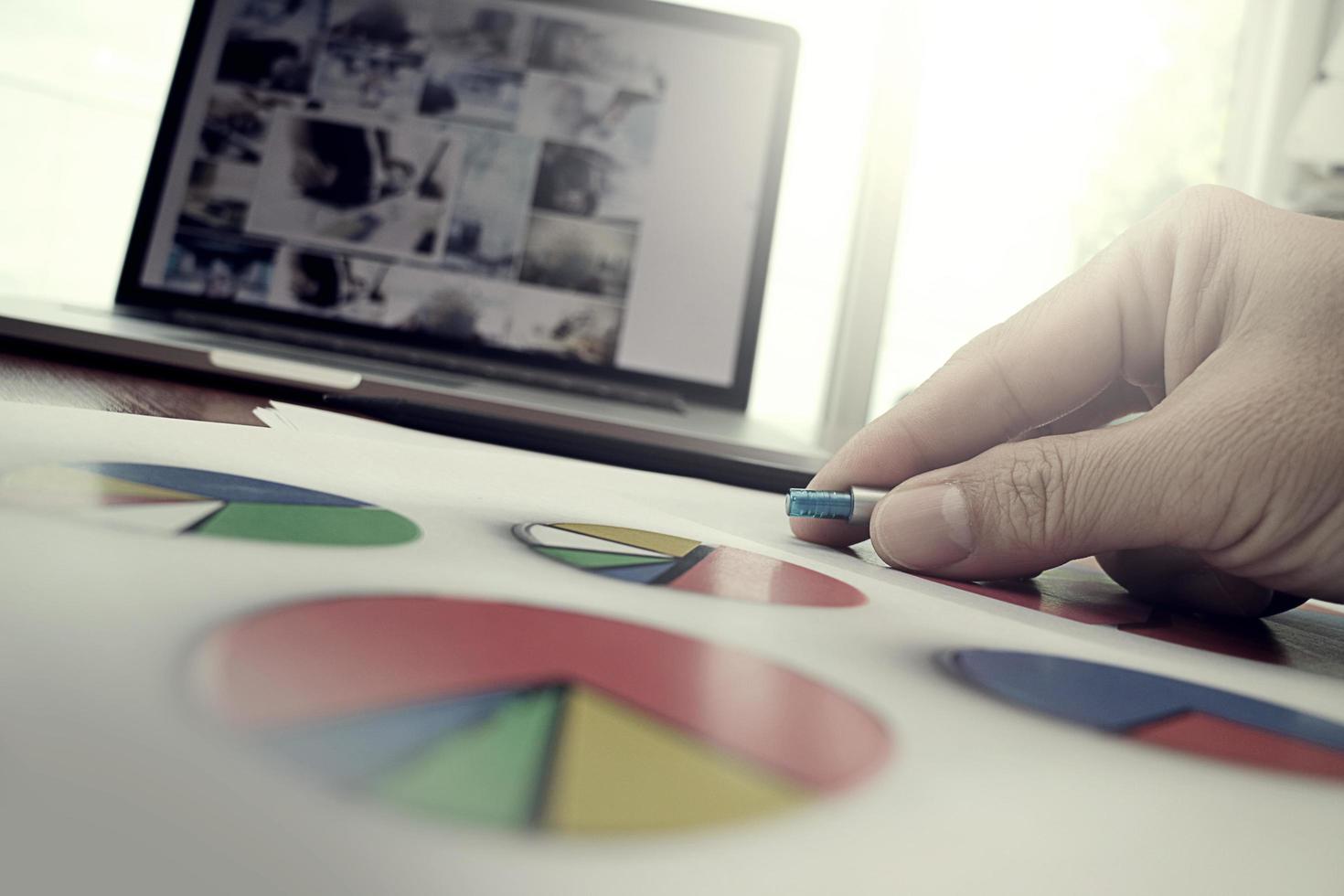 business documents on office table with smart phone and laptop computer and graph business with social network diagram and man working in the background photo