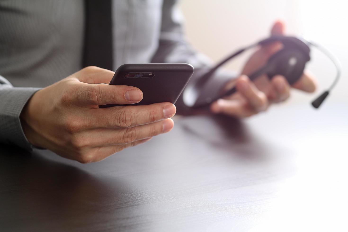 businessman using VOIP headset with mobile phone and concept communication call center on wooden desk photo