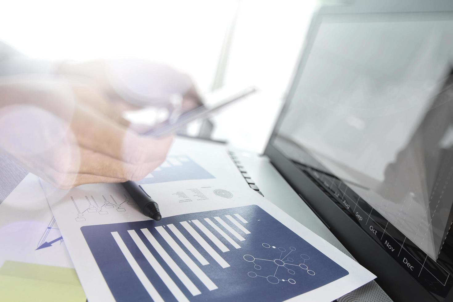 documentos de negocios en la mesa de oficina con teléfono inteligente y tableta digital y diagrama de negocios gráfico y hombre trabajando en segundo plano foto