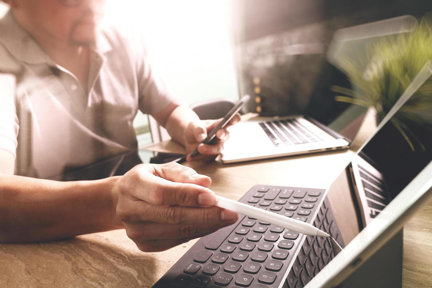 subcontratar a un desarrollador que trabaja en un escritorio de mármol que trabaja en una computadora portátil, software de aplicación móvil y teclado inteligente de base de tableta digital, servidor compacto, efecto de llamarada solar foto