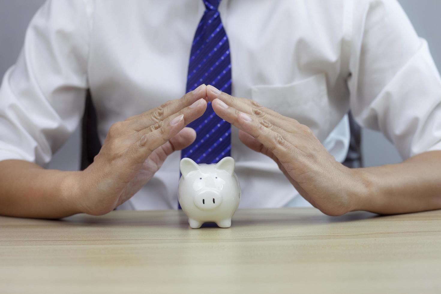Piggy security concept, insurance for real estate, protecting gesture of man and Piggy model. photo