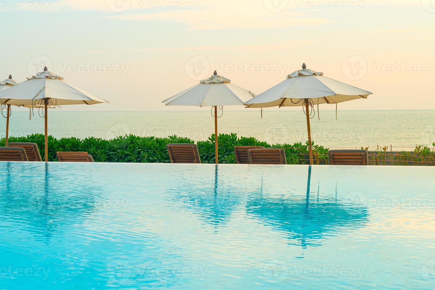 umbrella with bed pool around swimming pool with ocean sea background photo