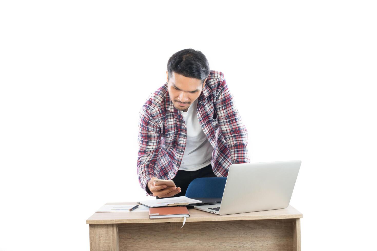 Young businessman looking at business chart in hand sitting at his working place isolated on white background. photo