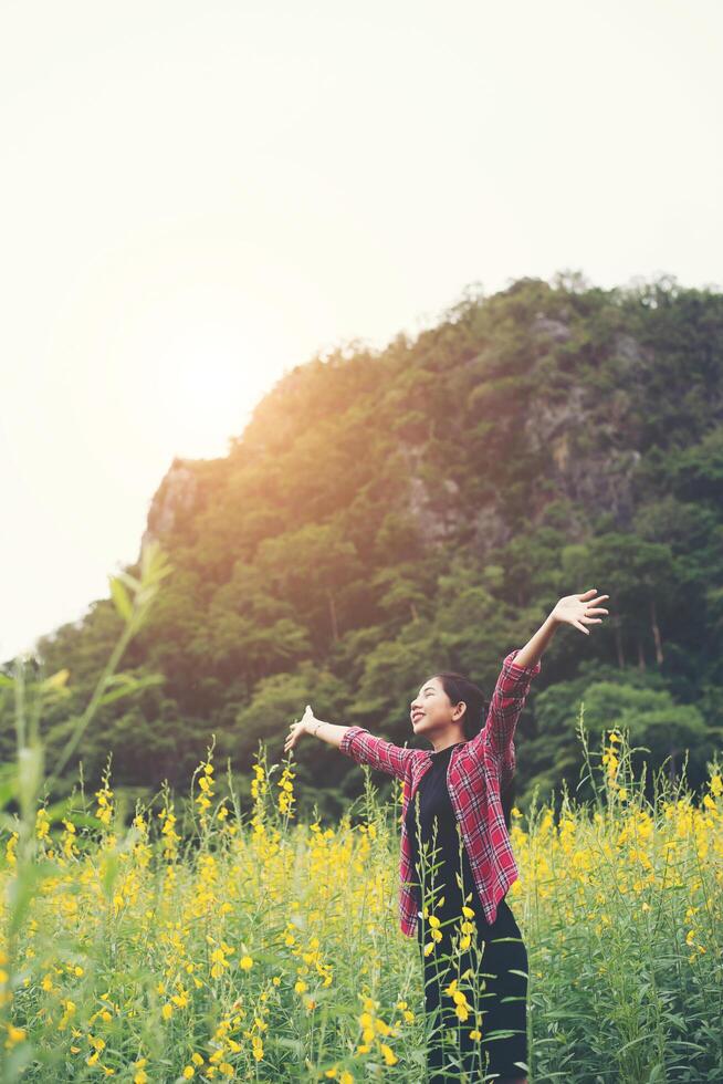 Young beautiful woman standing in the flower field enjoyment. photo