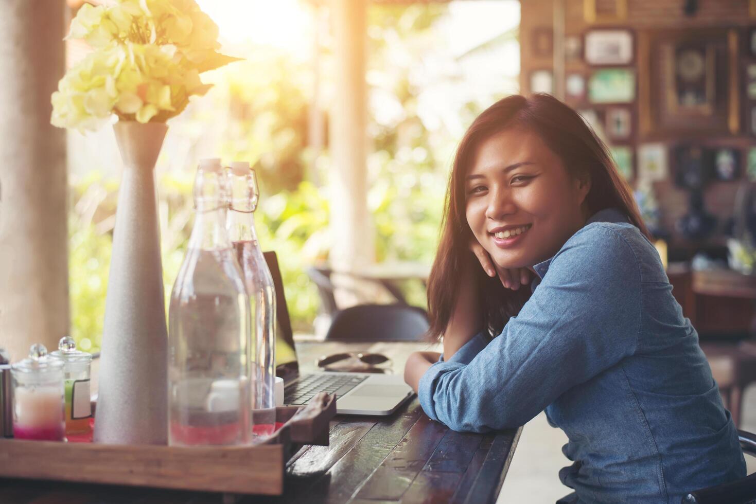 mujer joven inconformista con café y portátil. retrato de una hermosa mujer sonriente sentada en un café, relajándose. concepto de estilo de vida de la mujer. foto