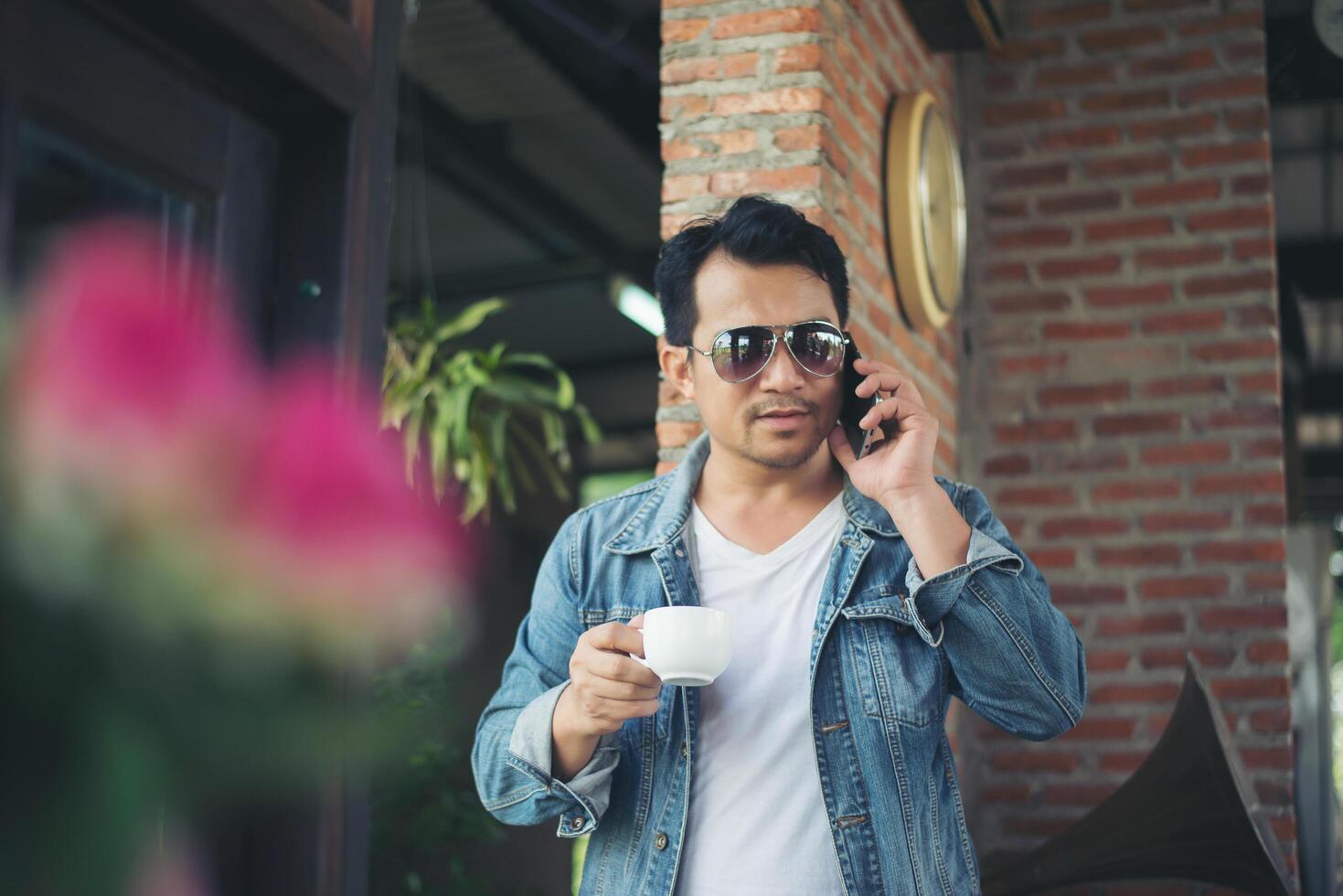 Hipster man holding a cup of coffee and walk in the coffee shop, Relaxing talking on phone. photo