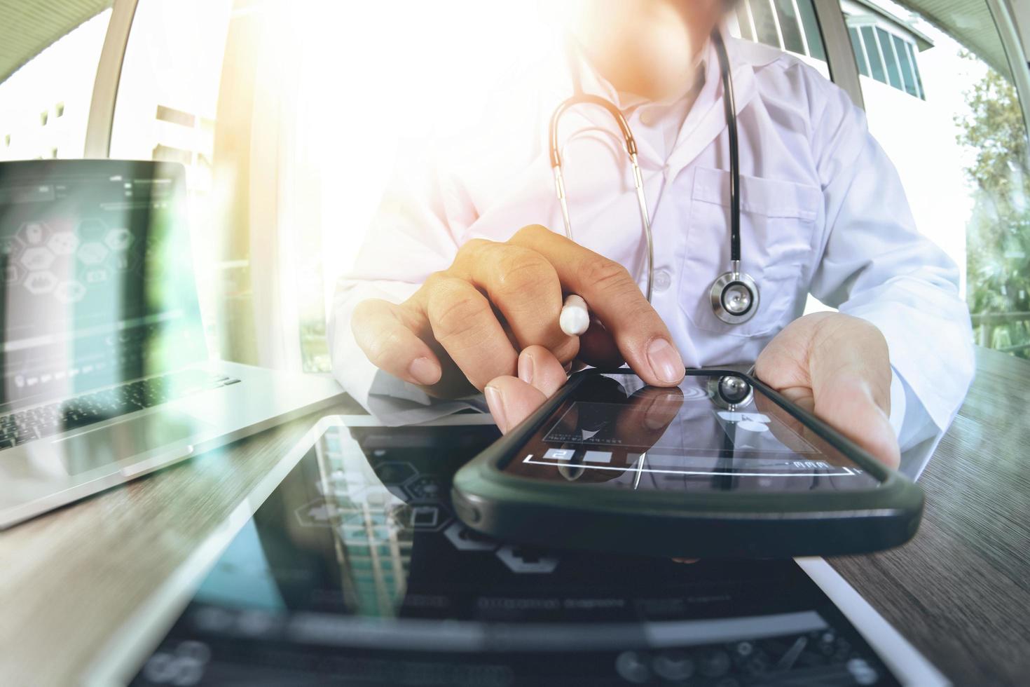 doctor en medicina trabajando a mano con un teléfono inteligente moderno y una tableta digital con estetoscopio como concepto de red médica foto