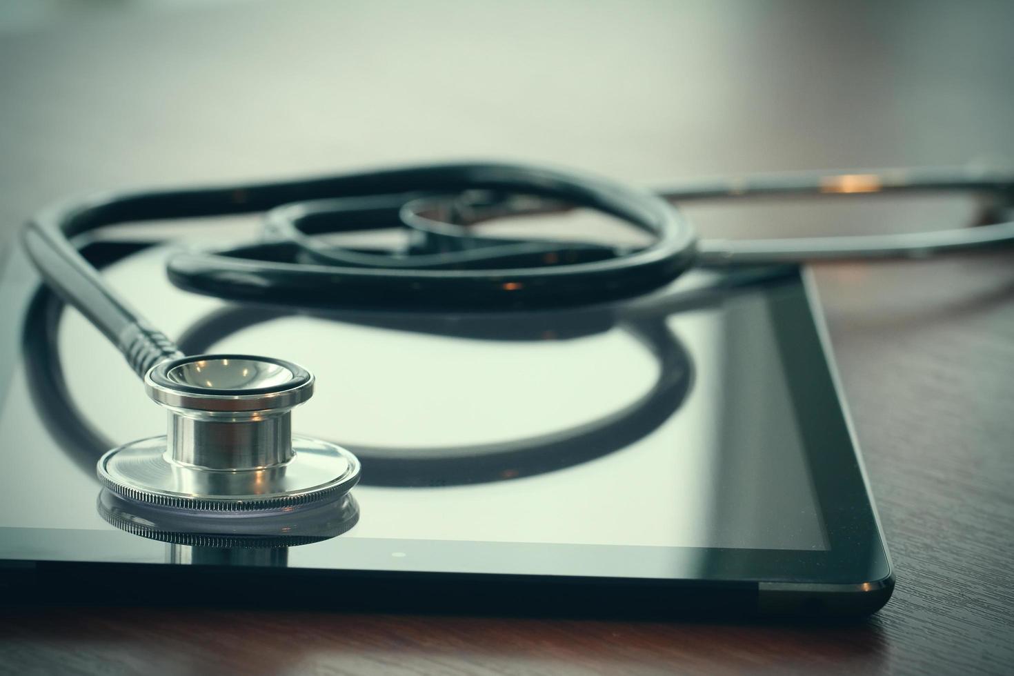 Studio macro of a stethoscope and digital tablet with shallow DOF evenly matched abstract on wood table background copy space photo