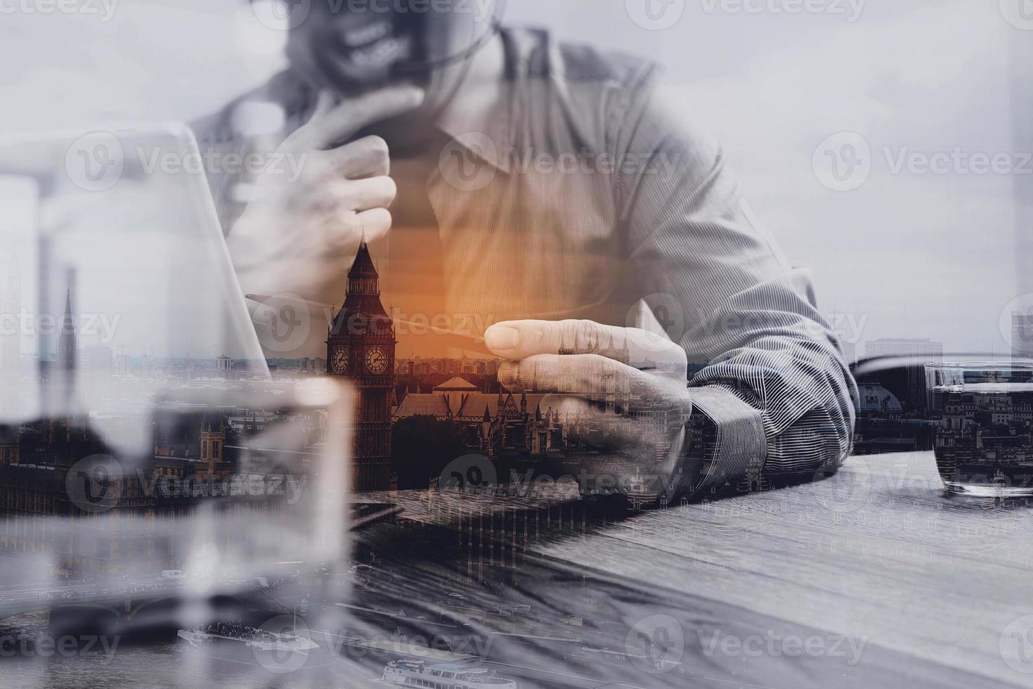 Double exposure of business man using VOIP headset with digital tablet computer docking smart keyboard, concept communication, it support,London city,on wood desk photo