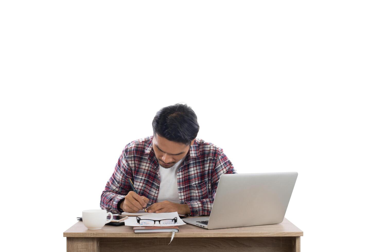 Young businessman  looking and writing on his notepad sitting at his working place isolated on white background. photo