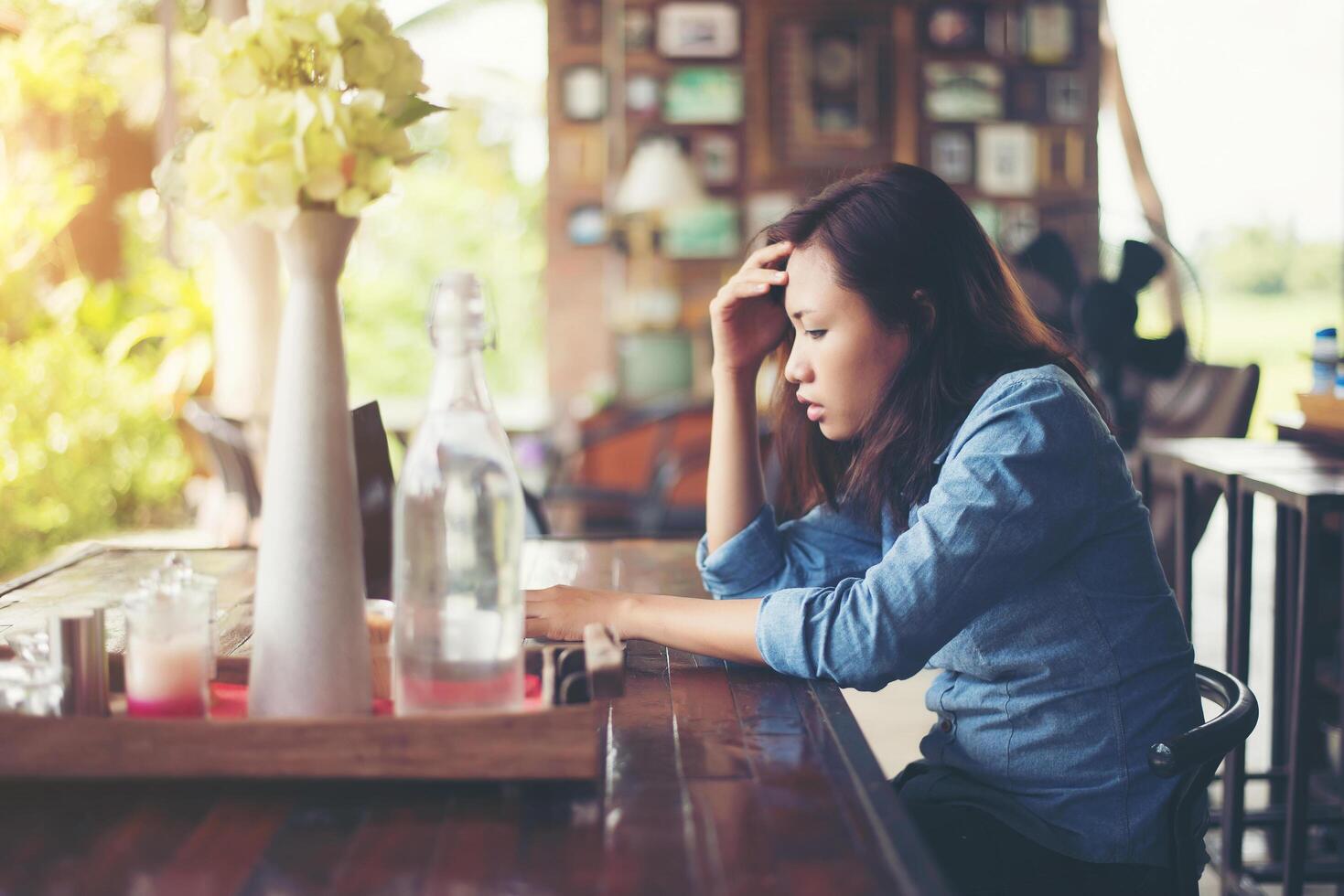 mujer joven sentada en un café con su computadora portátil, estresante para el trabajo. foto