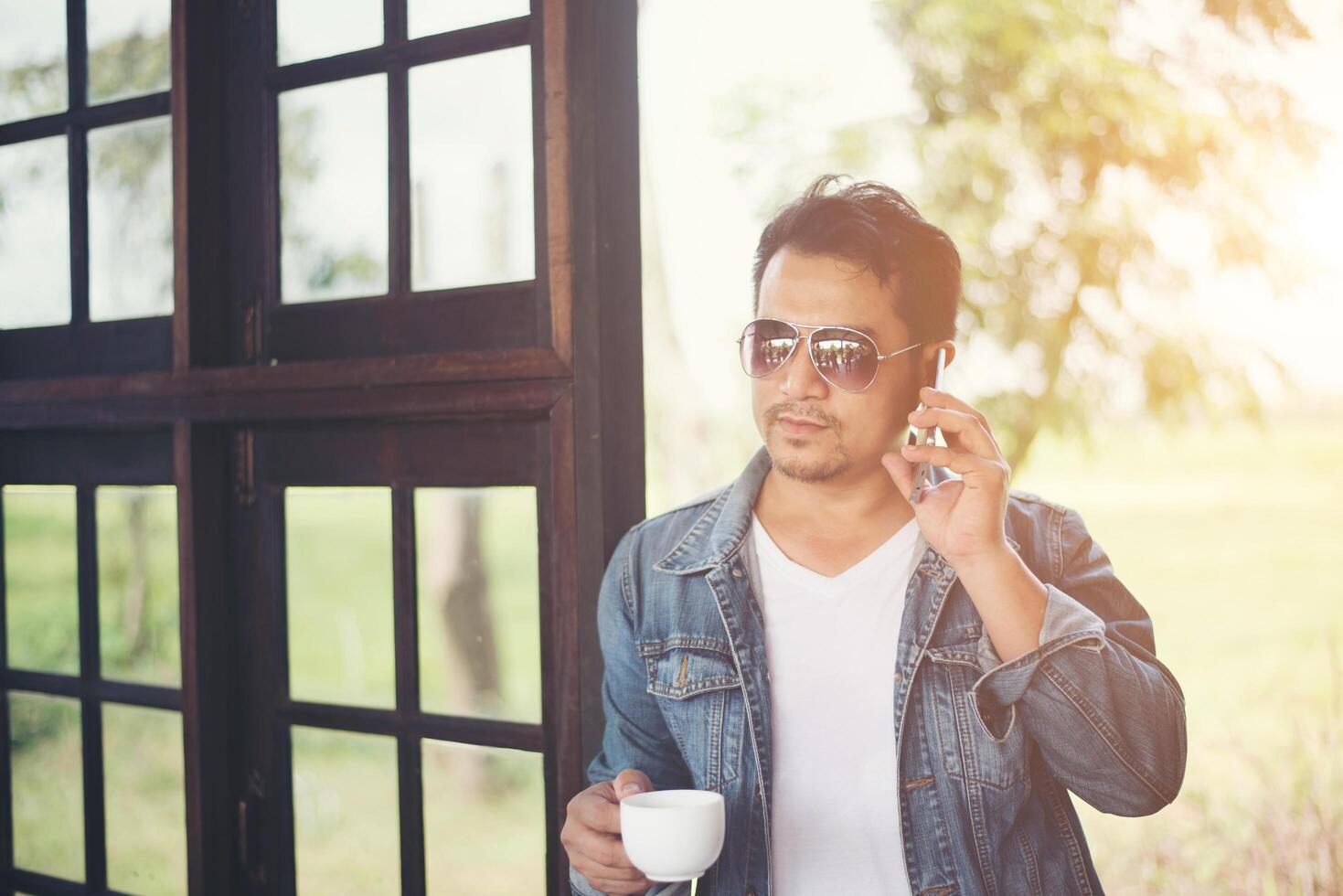 Hipster man holding a cup of coffee and walk in the coffee shop, Relaxing talking on phone. photo