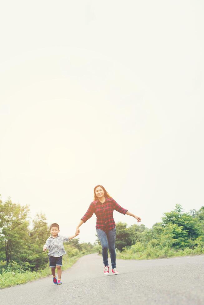 Little boy holding his mother hand running on the street enjoy good time together look so nice. photo