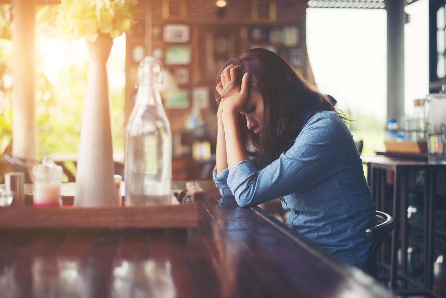 mujer joven sentada en un café con su computadora portátil, estresante para el trabajo. foto