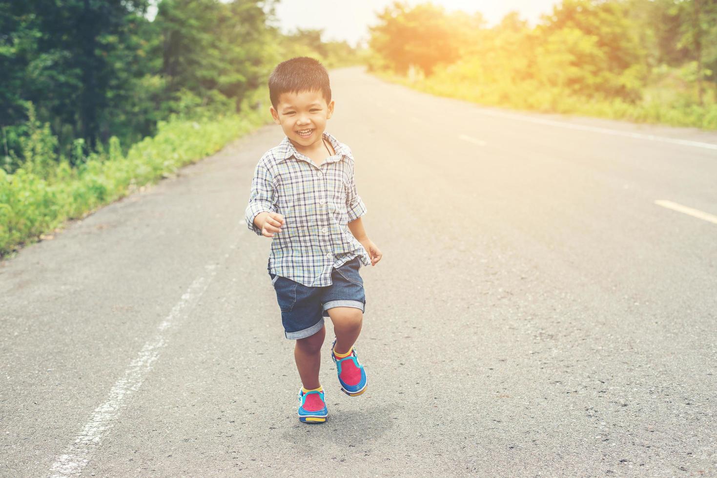 niño feliz en movimiento, sonriente corriendo en la calle. foto