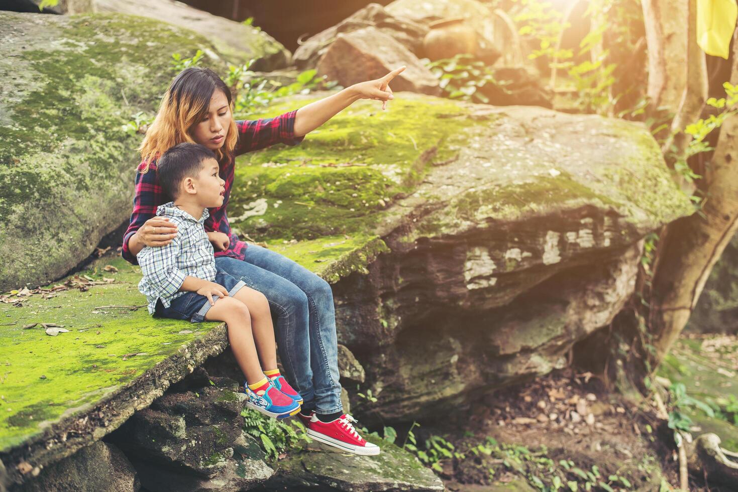 Mother and her little son sitting at the cliffside pointing finger to the sky. photo