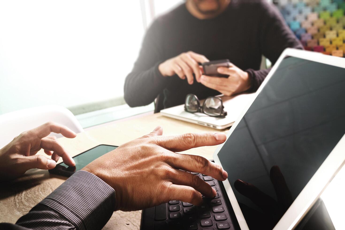 dos colegas diseñadores web discutiendo datos y teclado de acoplamiento de tableta digital y computadora portátil con teléfono inteligente y diagrama de diseño en escritorio de mármol, efecto de luz solar foto