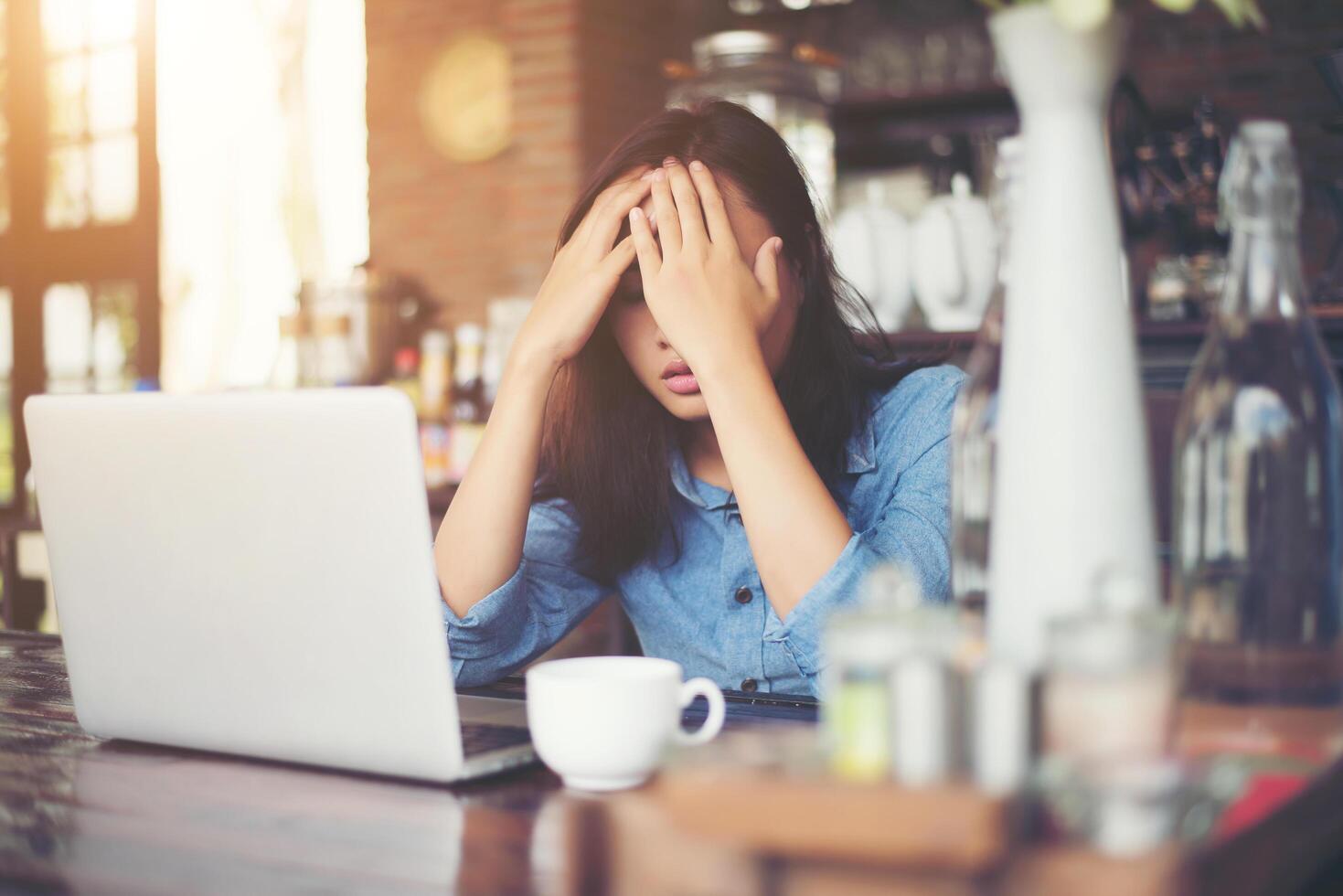 mujer joven sentada en un café con su computadora portátil, estresante para el trabajo. foto