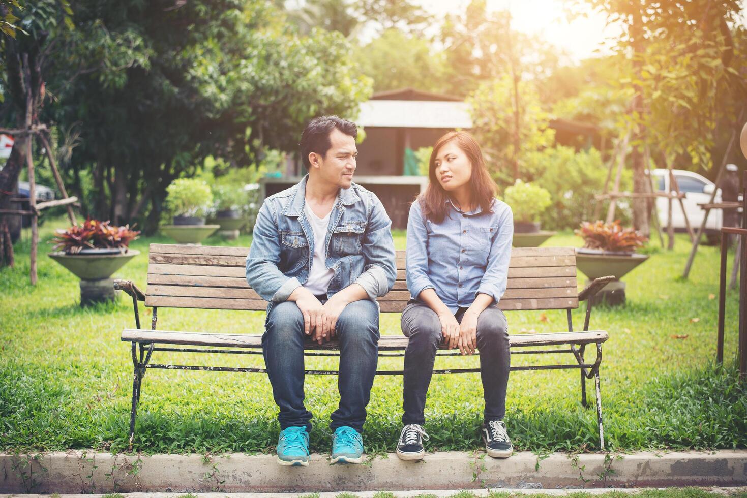 Young smiling couple looking on each other while sitting on bench, Dating time together. photo