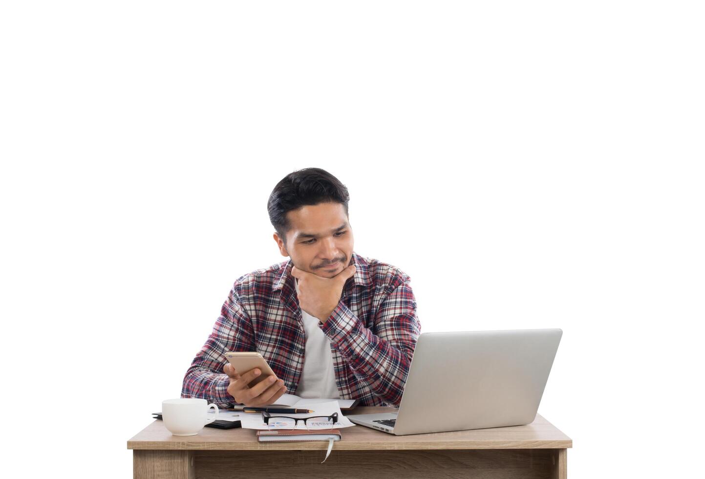 Thoughtful young man  looking at laptop while sitting at his working place isolated on white background. photo