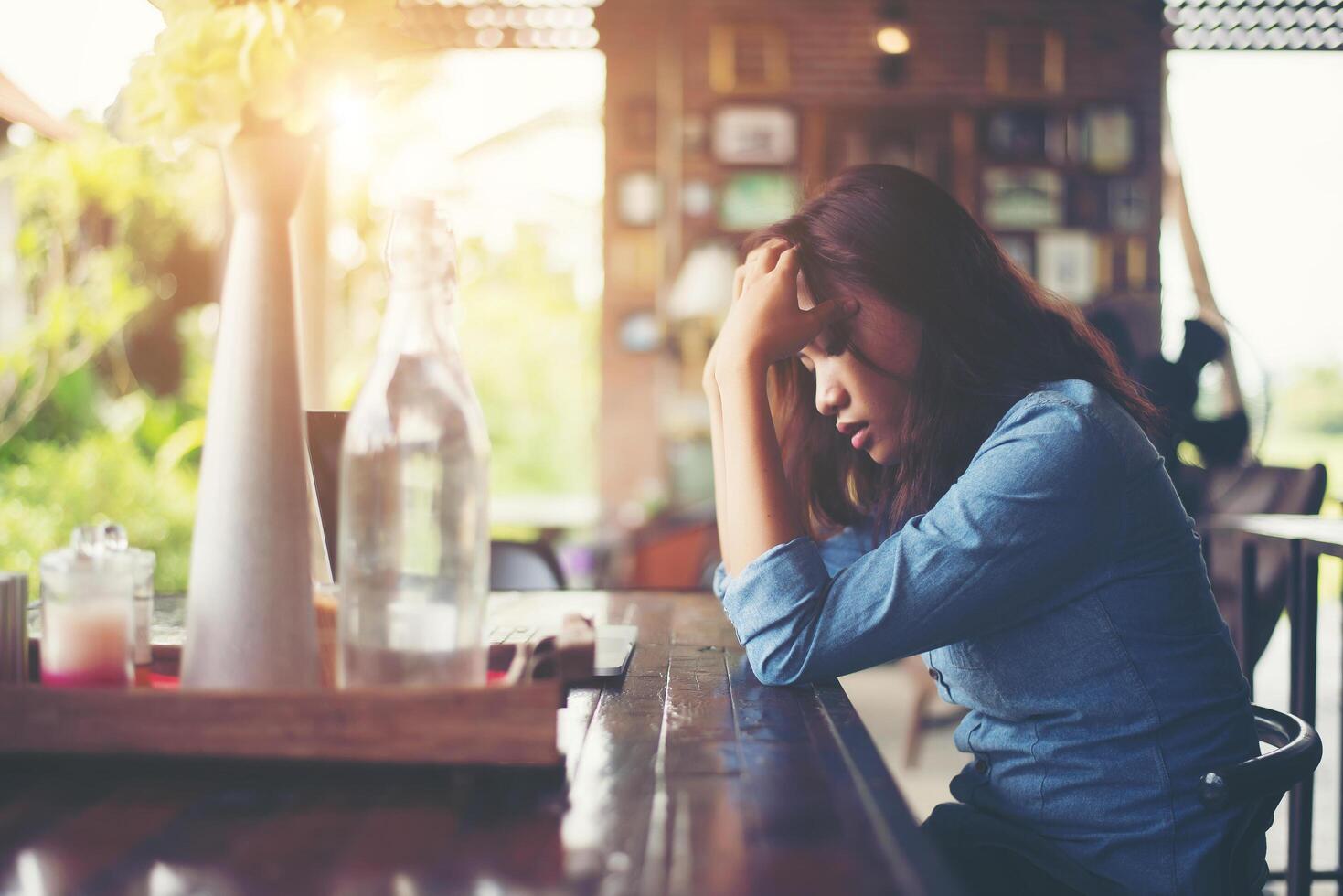 mujer joven sentada en un café con su computadora portátil, estresante para el trabajo. foto