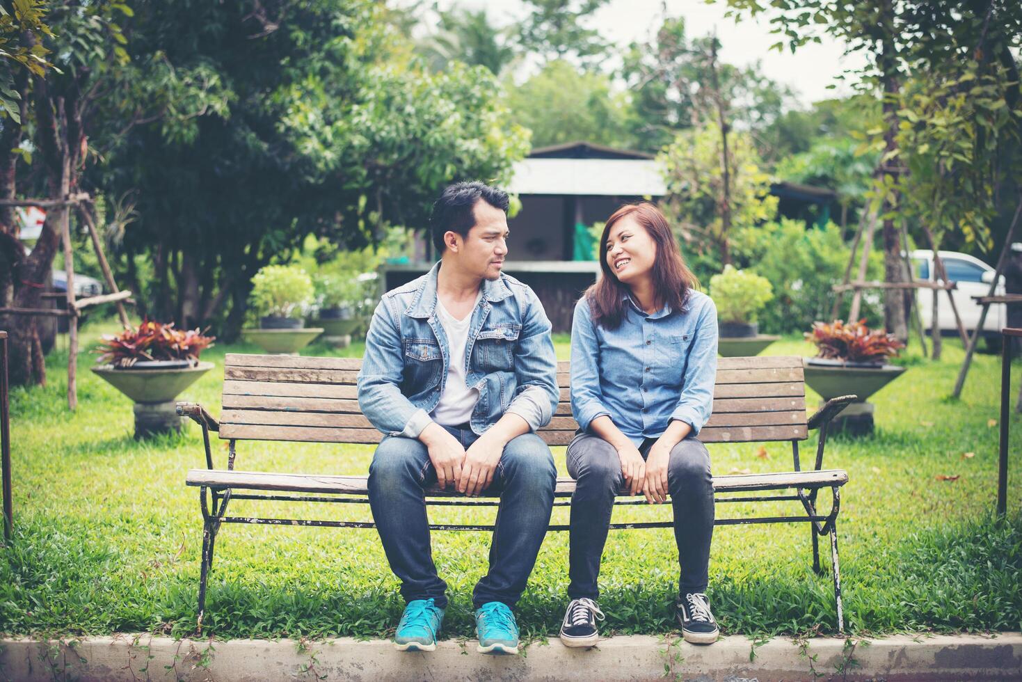 Young smiling couple looking on each other while sitting on bench, Dating time together. photo