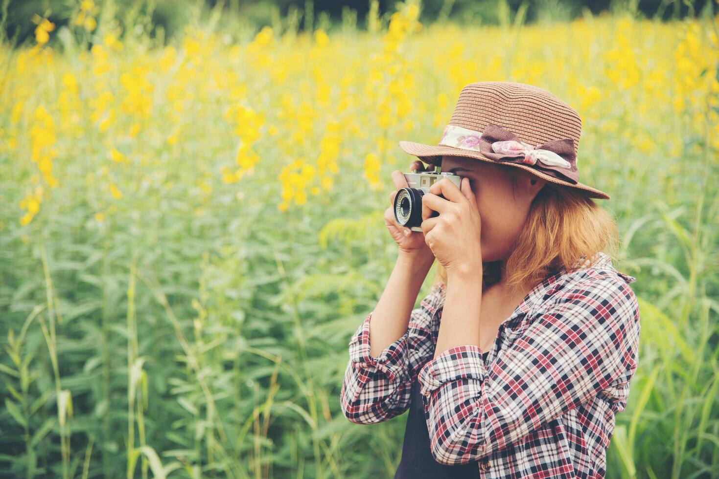 mujer feliz en el campo de flores amarillas con cámara retro al aire libre, disfrutando de la naturaleza. foto