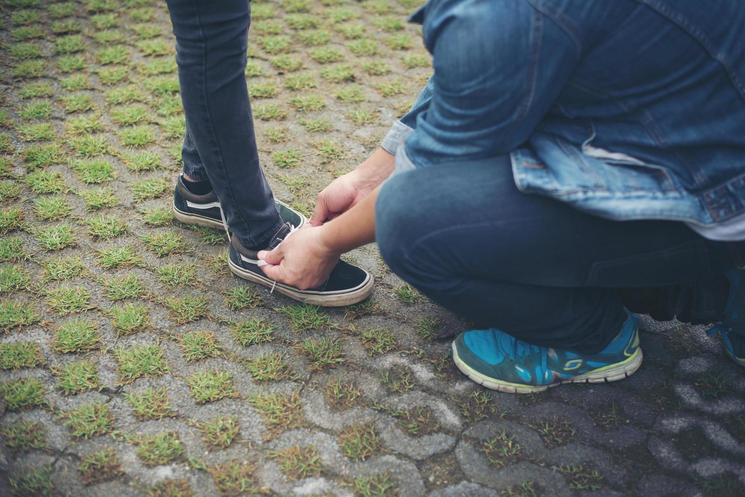 novio hipster atando zapatos a sus chicas mientras se relaja en vacaciones, concepto de pareja enamorada. foto