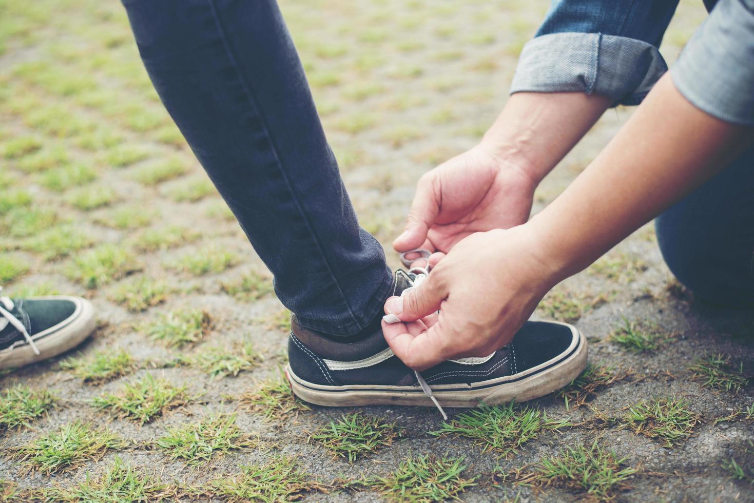 novio hipster atando zapatos a sus chicas mientras se relaja en vacaciones, concepto de pareja enamorada. foto