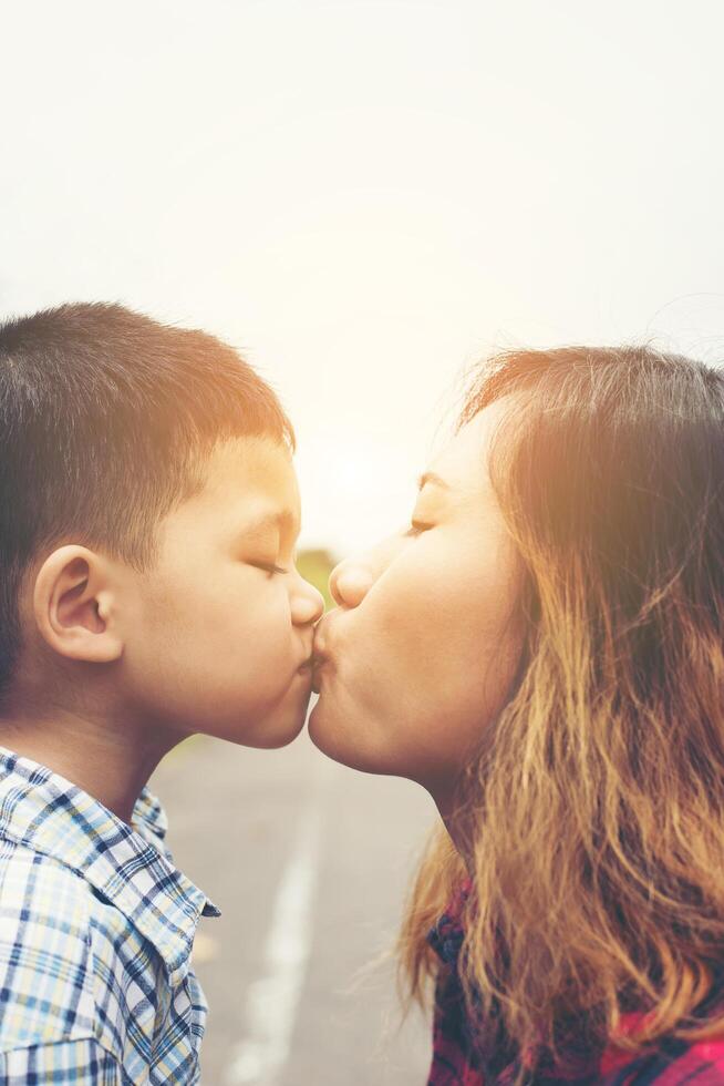 Little boy kissing his mom with the natural roadside. photo