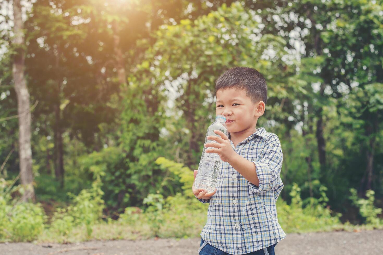 Little cute asian boy drink water on the roadside. photo