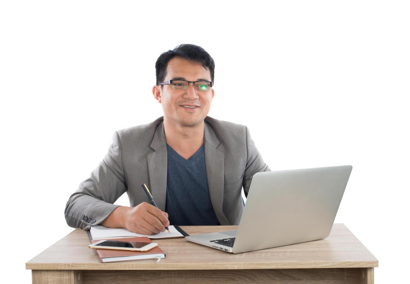 businessman writing notes on a writing pad while sitting at his desk behind his new notebook isolated on white background. photo