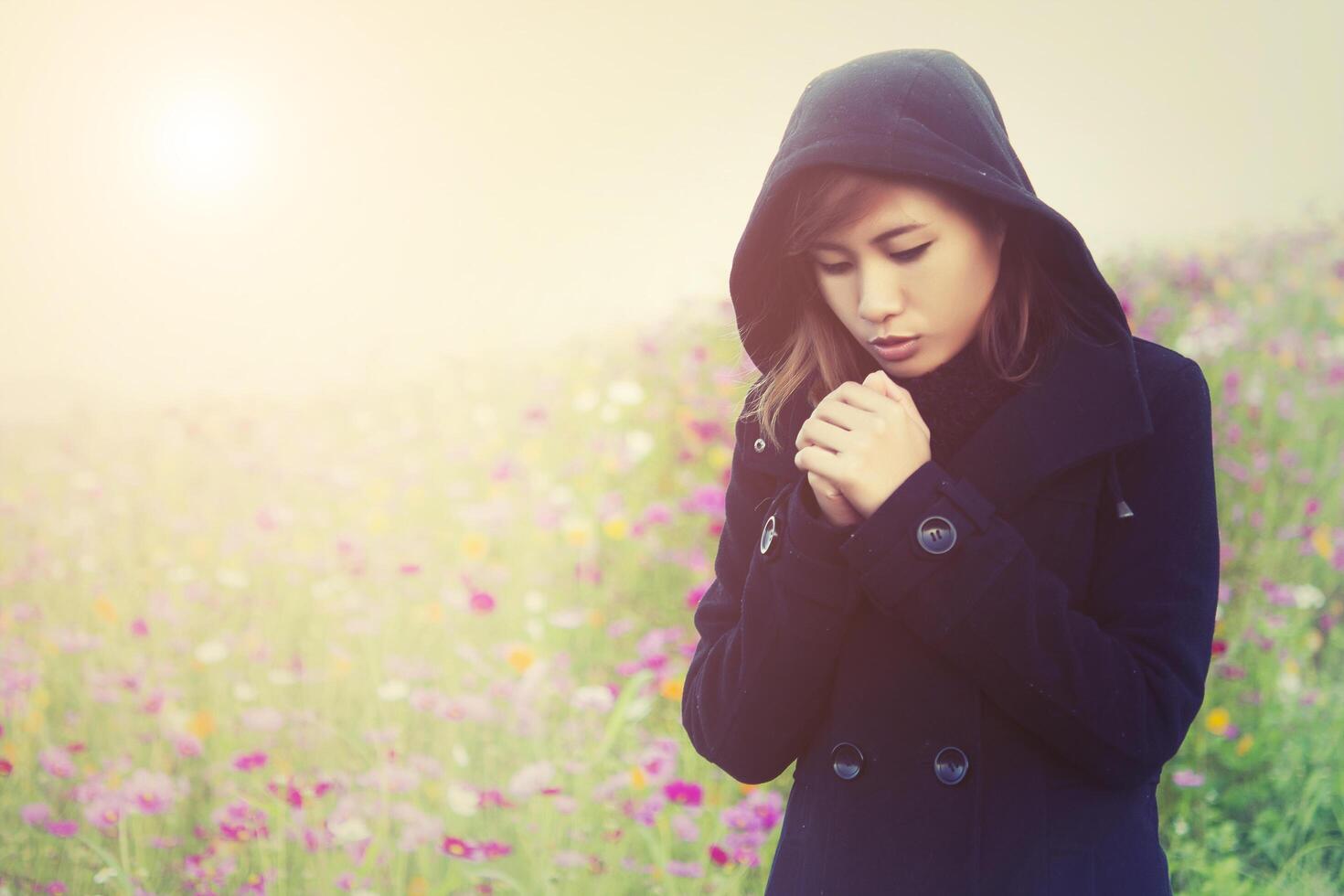 Young woman wearing black cloth very cold in flower garden photo