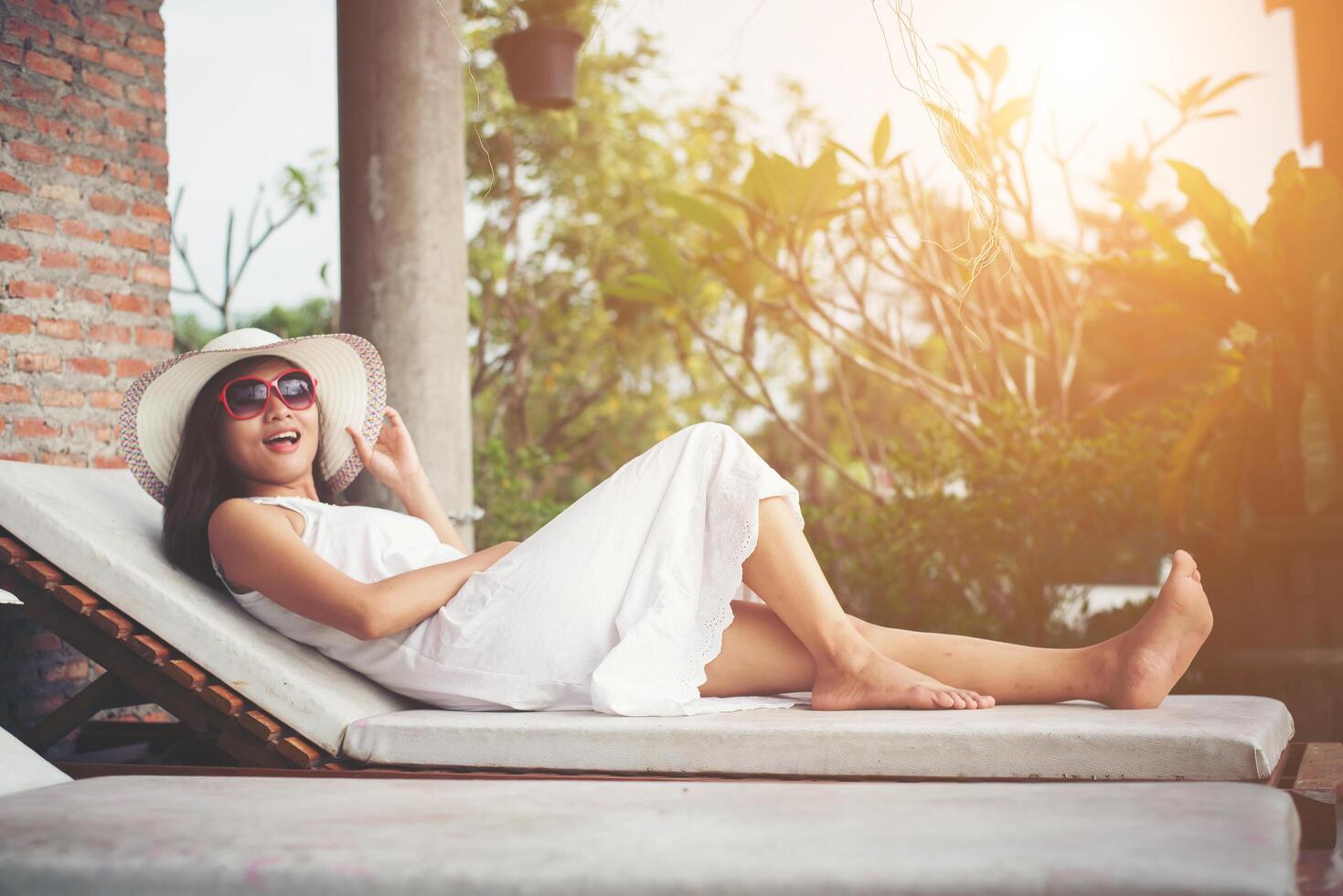 Portrait of charming woman relaxing on the deck chair outdoors with hat and glasses. photo