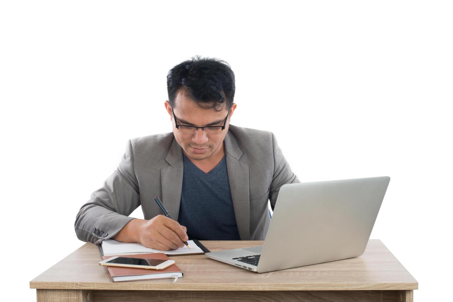 businessman writing notes on a writing pad while sitting at his desk behind his new notebook isolated on white background. photo