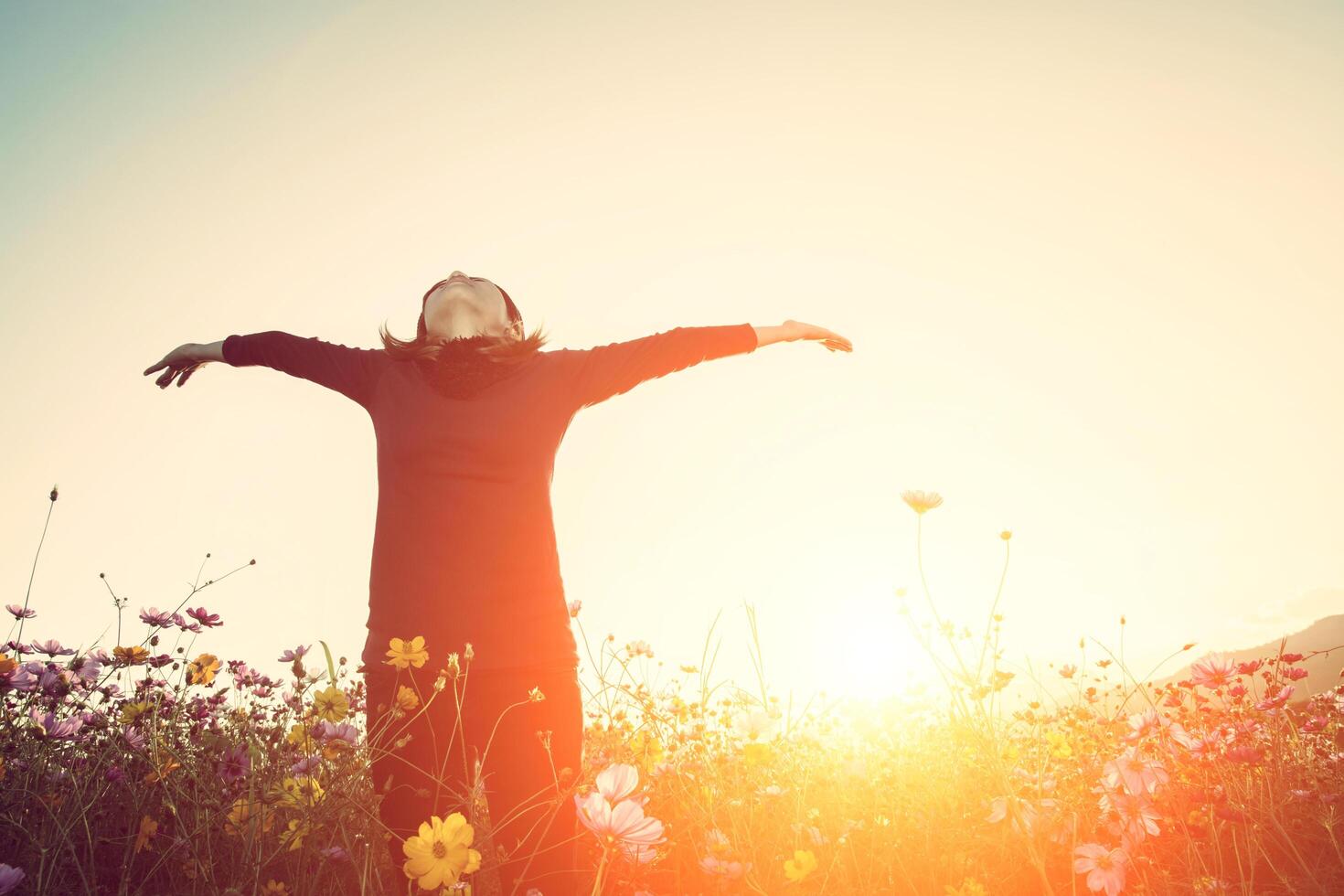 concepto de estilo de vida - hermosa mujer feliz disfrutando del aire fresco en el campo de flores del cosmos foto