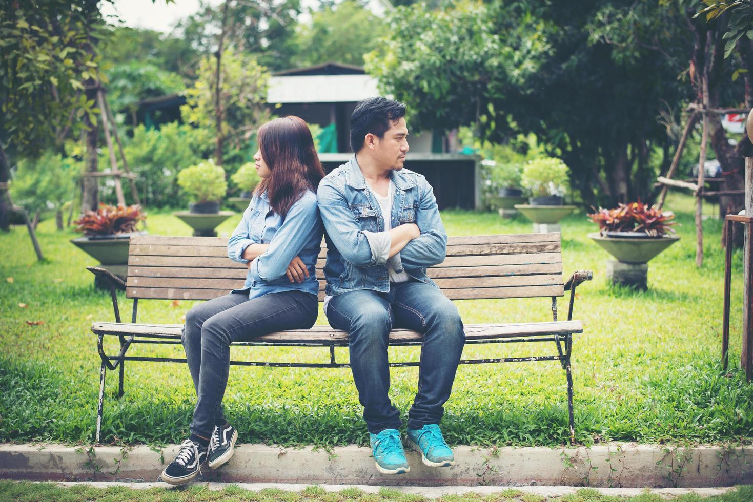Displeased young couple sitting on bench in park, Couple lifestyle concept. photo