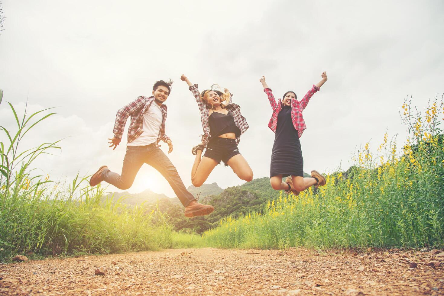 Group of Teenagers Jumping at yellow flower field,enjoying with nature and fresh breeze against mountain behind. photo