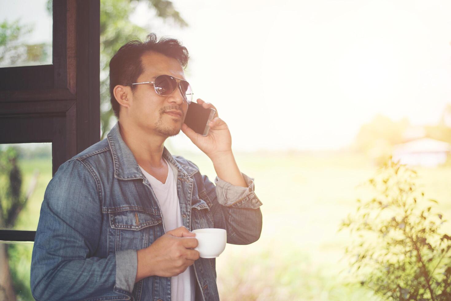 Hipster man holding a cup of coffee and walk in the coffee shop, Relaxing talking on phone. photo