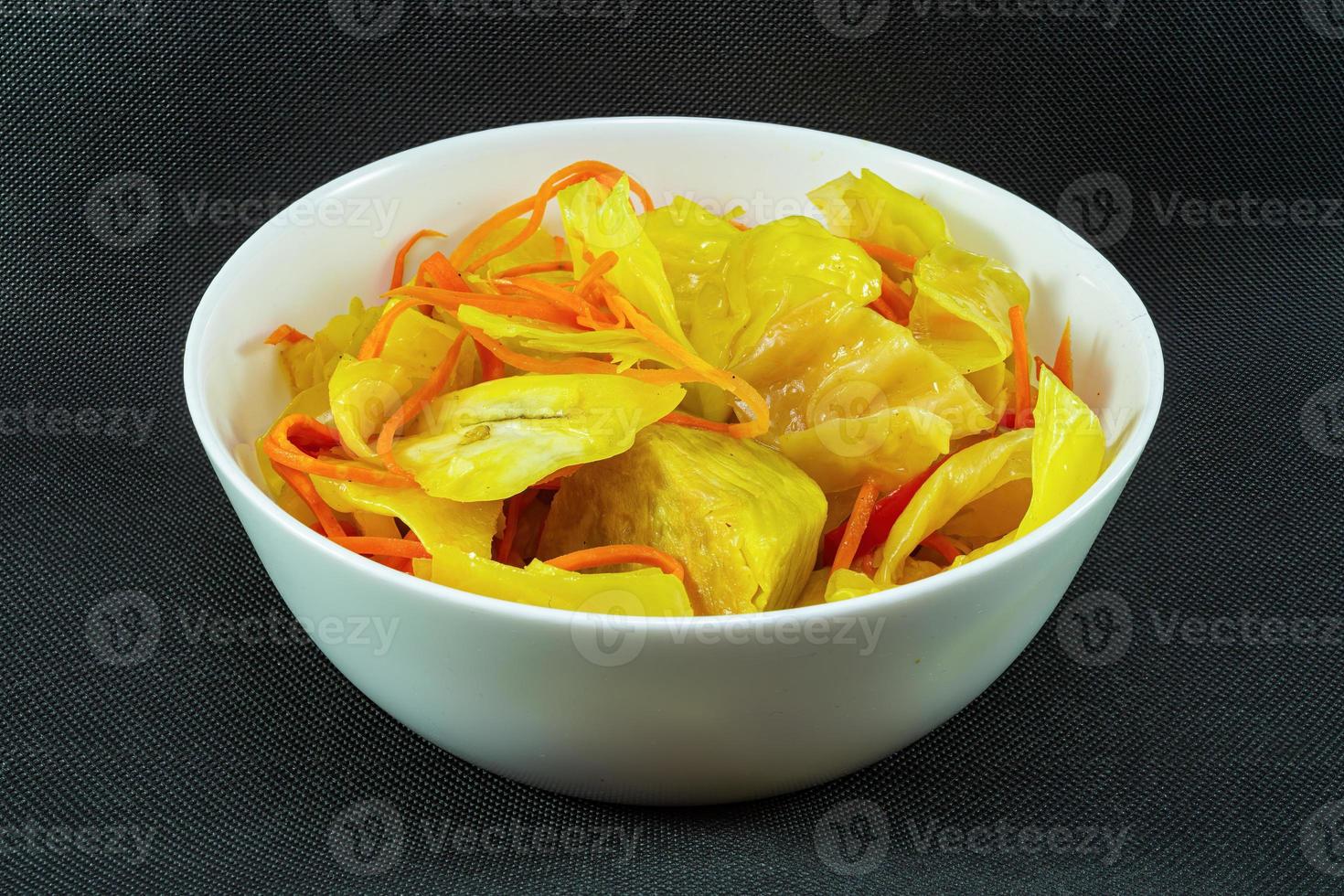 Pickled cabbage with curry and carrots in a plate on a black background photo