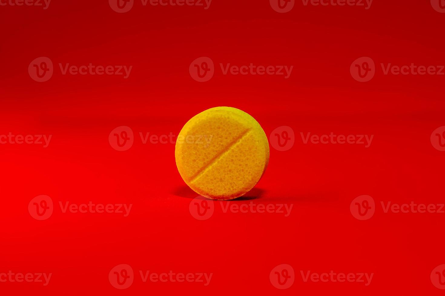 Yellow one pill on a bright red background close-up. Place for your text. Selective focus. photo